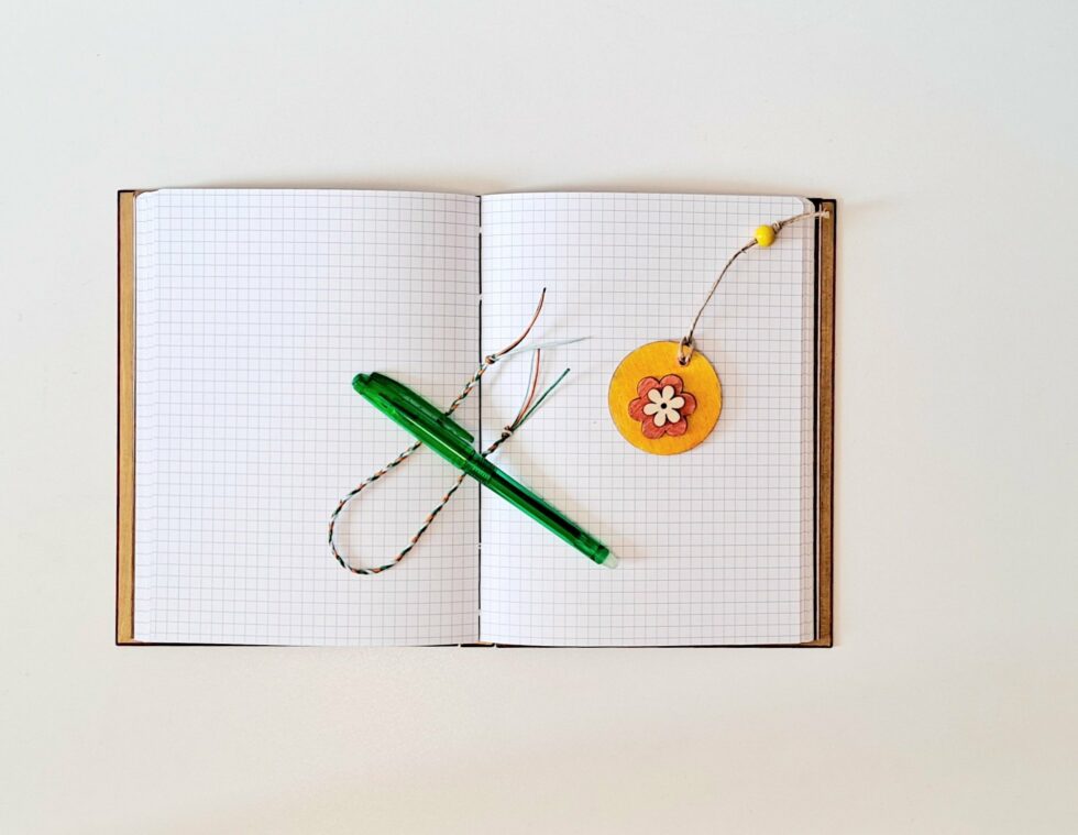 Carnet CAPUCINE, vue intérieure ouverte sur pages avec stylo vert et marque page fleur.