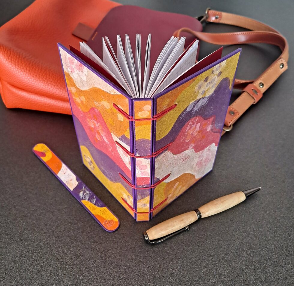 Carnet PASTORAL vue debout ouvert recto verso avec stylo en bois et marque page en bois peint.