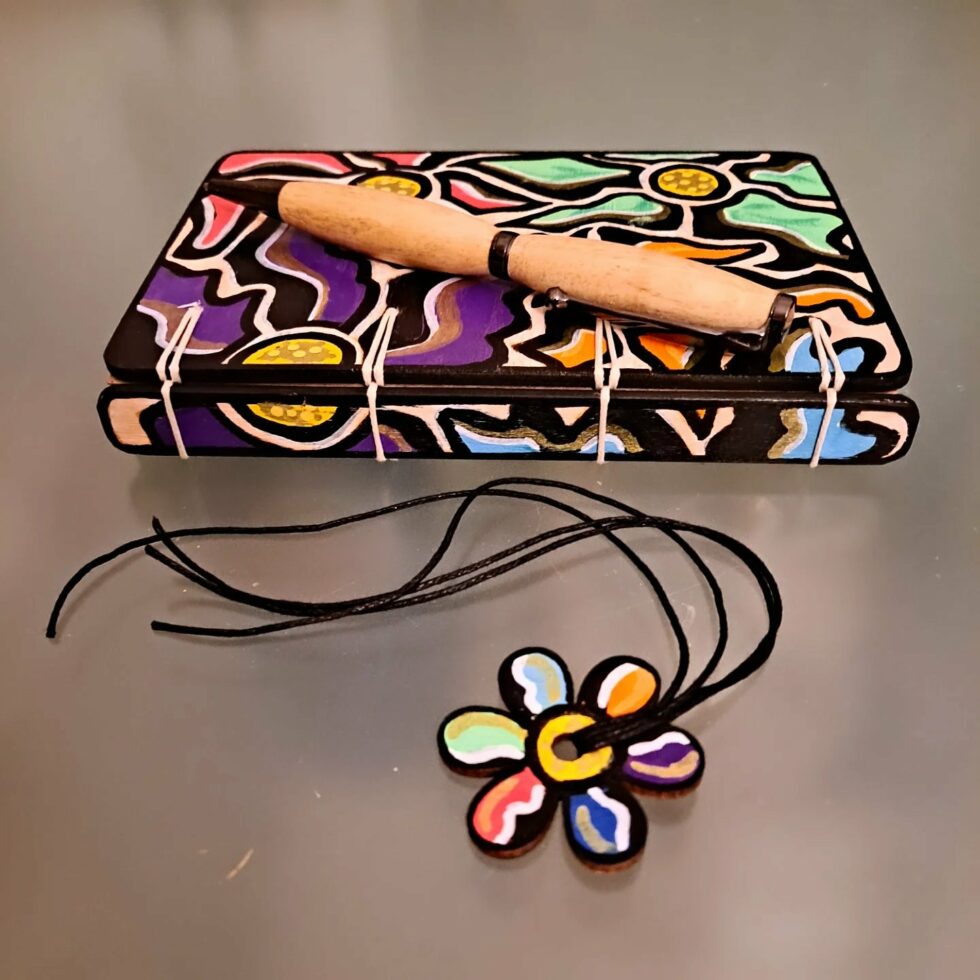 Carnet FLEUR, vue recto sur dos avec couverture en bois peint avec marque-pages en bois peint et stylo.