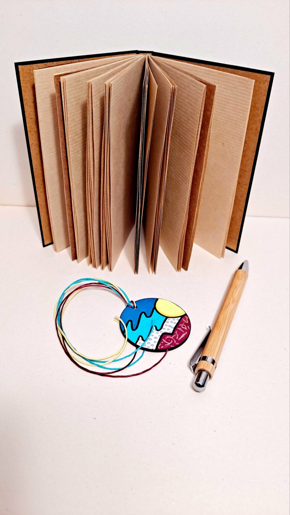 Carnet RÉGATE vue ouverte debout sur pages avec marque-pages et stylo en bois.