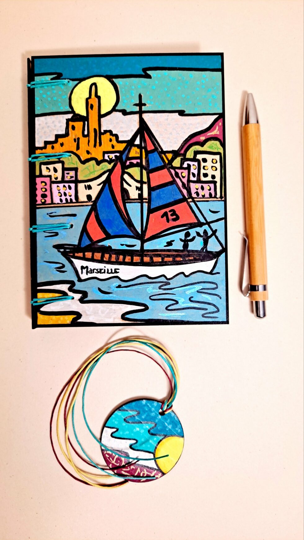 Carnet RÉGATE vue recto face avec marque-pages et stylo en bois.